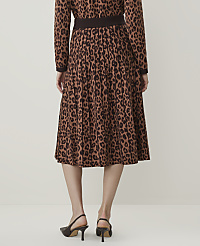 A person wearing a brown leopard-print pleated skirt and a matching top stands against a plain, light-colored background. carousel Product Image 3