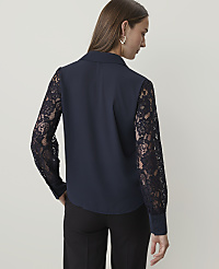 A woman in a dark blue blouse with lace sleeves stands against a plain, light background. carousel Product Image 2