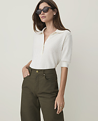 A woman in a white polo shirt and olive green pants stands against a plain, light background. carousel Product Image 1