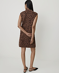 A woman in a leopard-print dress stands against a plain, light-colored background. carousel Product Image 2
