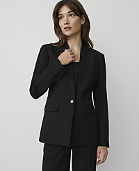 A woman in a black blazer stands against a plain gray background. carousel Product Image 1