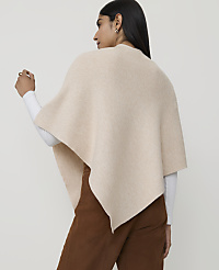 A woman in a cream-colored poncho and brown pants stands against a plain, light background. carousel Product Image 2
