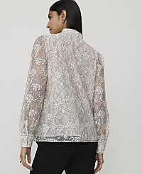 A woman in a white floral lace blouse stands against a plain background. carousel Product Image 2
