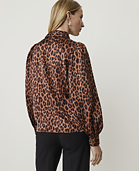 A woman in a leopard-print blouse and black pants stands against a plain white background. carousel Product Image 2