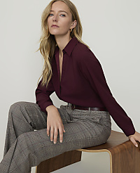 A blonde woman in a burgundy blouse and plaid pants sits on a wooden stool against a plain white background. carousel Product Image 3