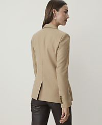 A woman in a tan blazer and dark pants stands against a plain, light-colored background. carousel Product Image 2