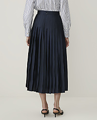 A person stands in the foreground wearing a navy pleated skirt and a striped shirt, against a plain, light-colored background. carousel Product Image 3