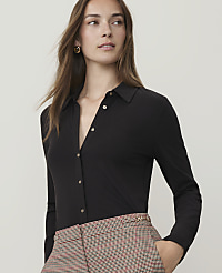 A woman in a black collared shirt and patterned pants stands against a plain background. carousel Product Image 1