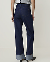 Dark wash denim jeans with wide, cuffed hems are worn against a plain, light background. carousel Product Image 3