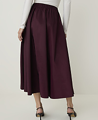 A person wearing a burgundy midi skirt and a white long-sleeved shirt stands against a plain light background. carousel Product Image 3