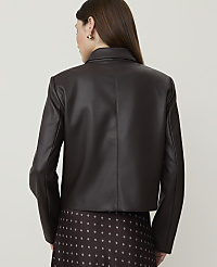A woman in a dark brown faux leather jacket and patterned skirt stands against a plain, light background. carousel Product Image 2