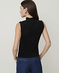 A woman in a black sleeveless turtleneck and blue jeans stands against a plain white background. carousel Product Image 2