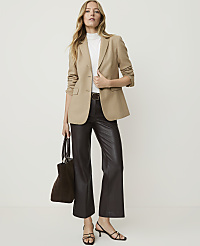 A woman in a tan blazer and dark pants stands against a plain white background, holding a dark tote bag. carousel Product Image 4