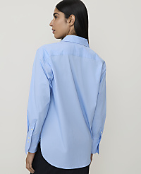 A woman in a light blue button-down shirt stands against a plain white background. carousel Product Image 2