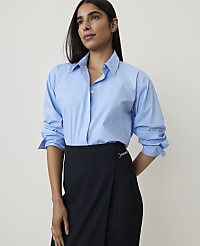 A woman in a light blue button-down shirt and a pinstripe skirt stands against a plain white background. carousel Product Image 1