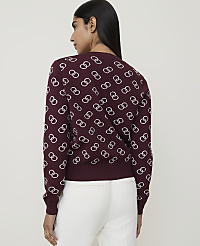 A woman in a maroon sweater with a white interlocking ring pattern stands against a plain background. carousel Product Image 2