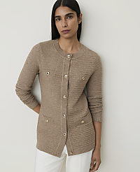 A woman in a beige cardigan and white pants stands against a plain, light gray background. carousel Product Image 1