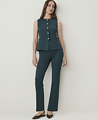 A woman in a teal vest and matching pants stands against a plain, light-colored wall. carousel Product Image 3