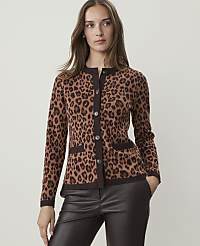 A woman in a leopard print cardigan and dark pants stands against a plain, light brown background. carousel Product Image 1