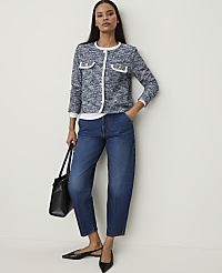 A woman in a tweed jacket and jeans stands against a plain white background, holding a black tote bag. carousel Product Image 3