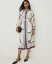 A woman in a cream-colored, patterned midi dress with a brown handbag and black heels stands against a plain white background. carousel Product Image 1