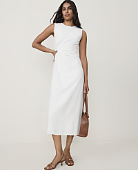 A woman in a white dress and brown sandals stands with a brown purse against a plain background. carousel Product Image 1