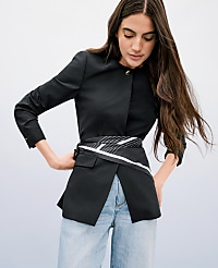 A woman in a black jacket and jeans stands against a light blue background. carousel Product Image 3