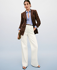 A woman in a brown blazer, striped shirt, and white wide-leg pants stands against a plain blue background, holding a leopard-print clutch. carousel Product Image 4