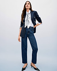 A woman in a navy blazer, white shirt, patterned scarf, and dark wash jeans stands against a light blue gradient background. carousel Product Image 4