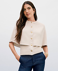 A woman in a cream-colored capelet and sweater stands against a plain, light background. carousel Product Image 3