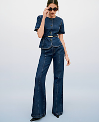 A woman in a denim peplum top and flared jeans poses against a gradient blue background. carousel Product Image 4