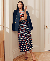 A woman in a striped top, navy blazer, and patterned skirt stands in a hallway with a wooden floor and white doors. carousel Product Image 4