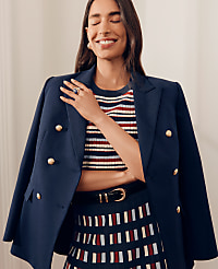 A smiling woman in a navy blazer and striped top poses against a plain, light-colored background. carousel Product Image 3