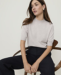 A blonde woman in a black turtleneck and denim jeans stands against a plain white background. carousel Product Image 1