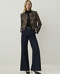 A woman in a patterned jacket and wide-leg jeans stands against a plain, light background. carousel Product Image 4