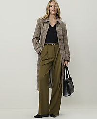 A woman in a plaid coat and olive green pants stands against a plain, light-colored background, holding a black handbag. carousel Product Image 1