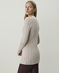 A woman in a beige cable-knit sweater and burgundy pants stands against a plain, light gray background. carousel Product Image 2