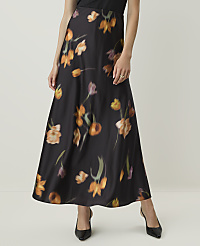 A woman in a black floral skirt and heels stands against a plain, light-colored background. carousel Product Image 2