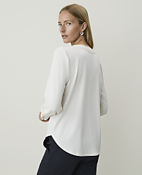 A woman in a white blouse and dark pants stands against a plain, light background. carousel Product Image 2