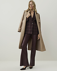 A woman in a plaid blazer and burgundy flared pants stands against a plain, light background, with a tan trench coat draped over her shoulders. carousel Product Image 1