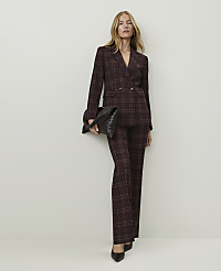 A woman in a plaid suit and holding a clutch stands against a plain, light-colored wall. carousel Product Image 1