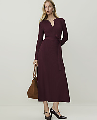 A woman in a burgundy ribbed dress and heels stands with a brown bag against a plain, light background. carousel Product Image 1