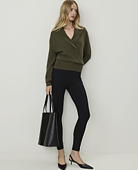 A woman in a green wrap sweater and black leggings stands with a black tote bag against a plain white background. carousel Product Image 1