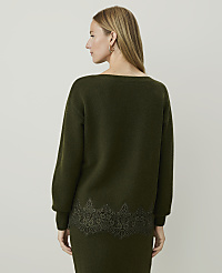 A woman in a green sweater with lace trim stands against a plain, light gray background. carousel Product Image 2