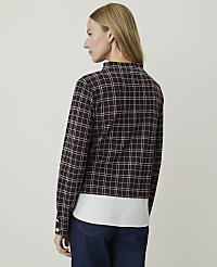 A woman in a plaid jacket and white shirt stands against a plain, light-colored background. carousel Product Image 2