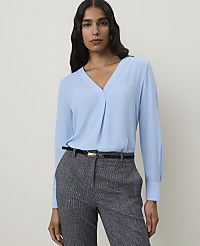 A woman in a light blue blouse and patterned pants stands against a plain background. carousel Product Image 1