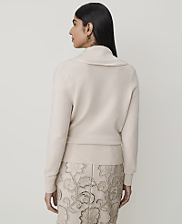 A woman in a cream cowl-neck sweater and a patterned skirt stands against a plain, light background. carousel Product Image 2