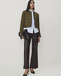 A woman in a tweed jacket and leather pants stands against a plain white background, holding a woven clutch. carousel Product Image 3