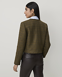 A woman in a textured green jacket and brown leather pants stands against a plain, light-colored background. carousel Product Image 2