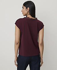 A woman in a maroon top and dark jeans stands against a plain white background. carousel Product Image 2